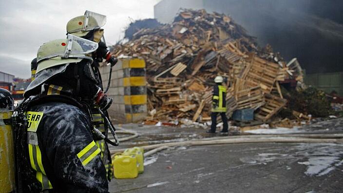 Zwei Feuerwehrleute mit Atemschutzmaske vor einem zerstörten Gebäude