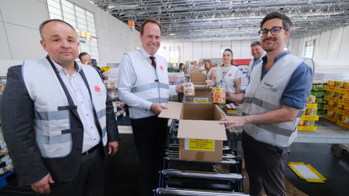 Helfer packen einen Karton mit Lebensmittelkonserven