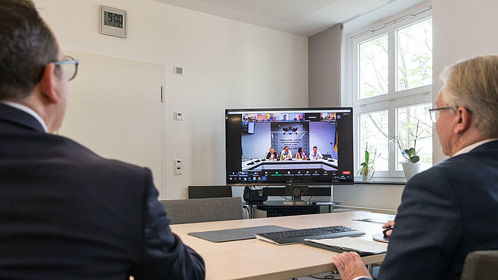 Zwei Menschen schauen auf einen Laptop während einer Videokonferenz