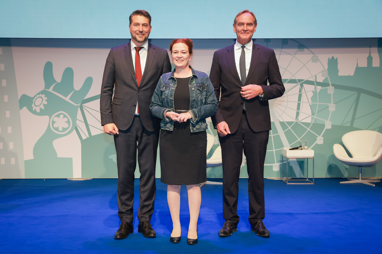 Uwe Conradt, Katja Dörner und Burkhard Jung stehen für ein Gruppenfoto auf einer Bühne.
