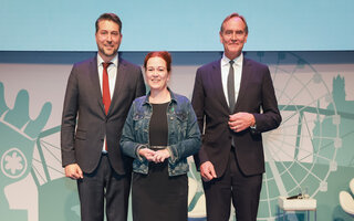 Uwe Conradt, Katja Dörner und Burkhard Jung stehen für ein Gruppenfoto auf einer Bühne.