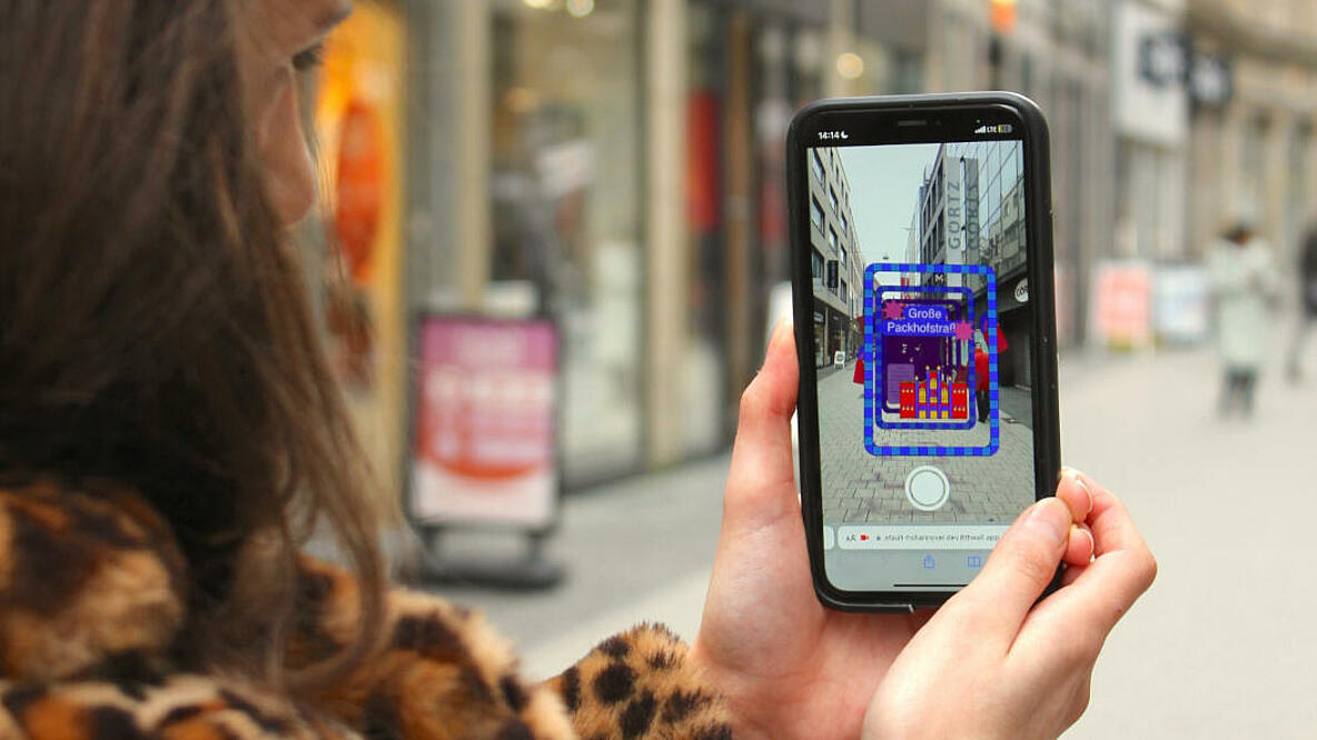 Eine Frau hält ein Smartphone und scannt damit ein Strassenschild.