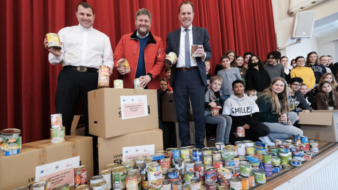 Eine Gruppe von Menschen steht hinter gepackten Karton und Lebensmittelkonserven