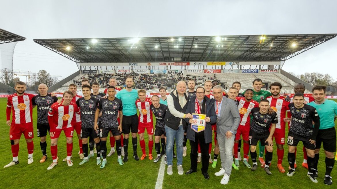 Drei Menschen stehen vor einer Fußballmannschaft in einem Stadion