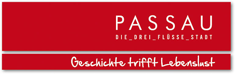 Es handelt sich bei dem Bild um das Logo der Stadt Passau, das aus zwei roten Balken besteht. Im oberen Balken steht in weißen Großbuchstaben "PASSAU - DIE DREI FLÜSSE STADT". Im Balken darunter steht in weißer Druckschrift "Geschichte trifft Lebenslust".