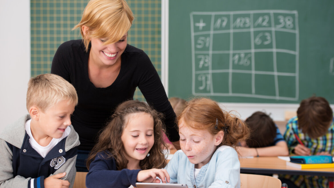 Lehrerin mit einer Gruppe von Grundschülerinnen und Grundschülern
