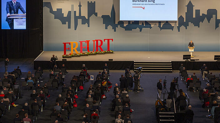 Blick von oben auf die Bühne der Hauptversammlung des Deutschen Städtetages. Burkhard Jung, Städtetagspräsident von Juni 2019 bis November 2021, hält die Begrüßungsrede vor den Delegierten aus den Städten in der Messe der Gastegeberstadt Erfurt. 