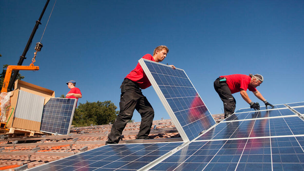 Handwerker setzen Solaranlage auf Hausdach