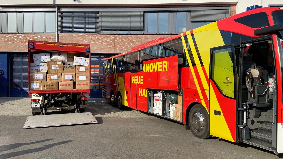 Feuerwehrwagen und -bus gefüllt mit Kisten mit Hilfslieferungen 