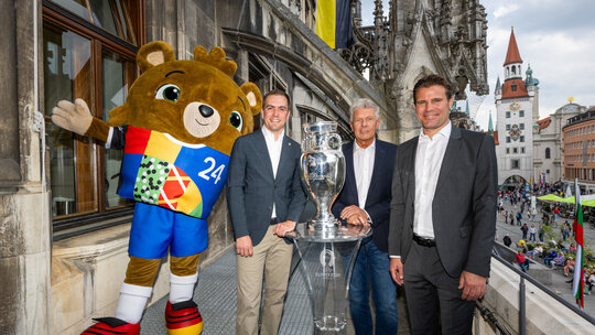 Der EM-Pokal auf dem Münchner Rathausbalkon mit Maskottchen Albärt (v.l.n.r.), Turnierdirektor Philipp Lahm, Oberbürgermeister Dieter Reiter und Host City Botschafter Dr. Felix Brych.