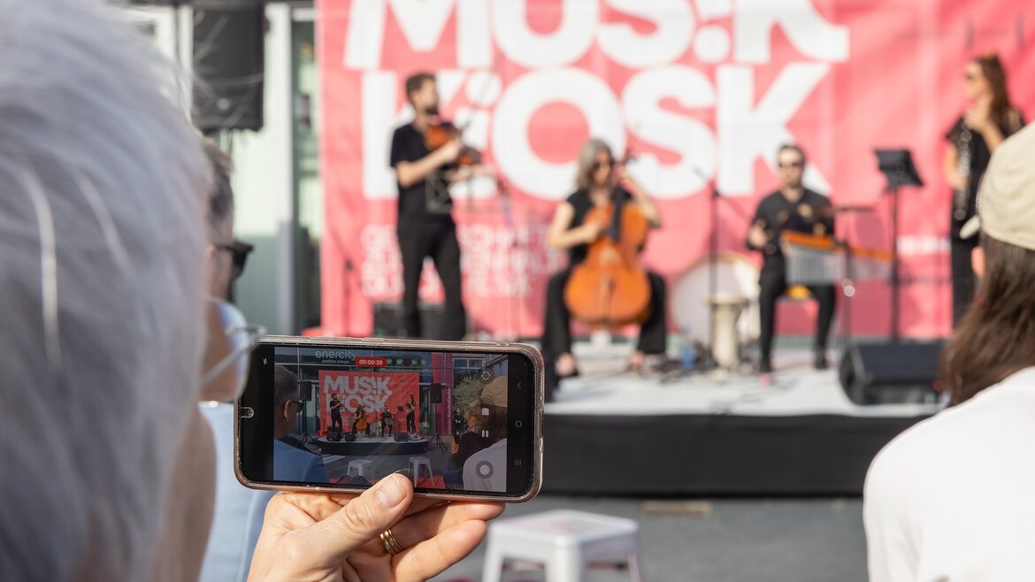 Blick auf ein Smartphone, mit dem ein Video einer Musikaufführung erstellt wird - Musikkiosk, Hannover