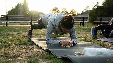 Sport in einem Düsseldorfer Park: Teilnehmerin macht auf einer Matte Gymnastik. 