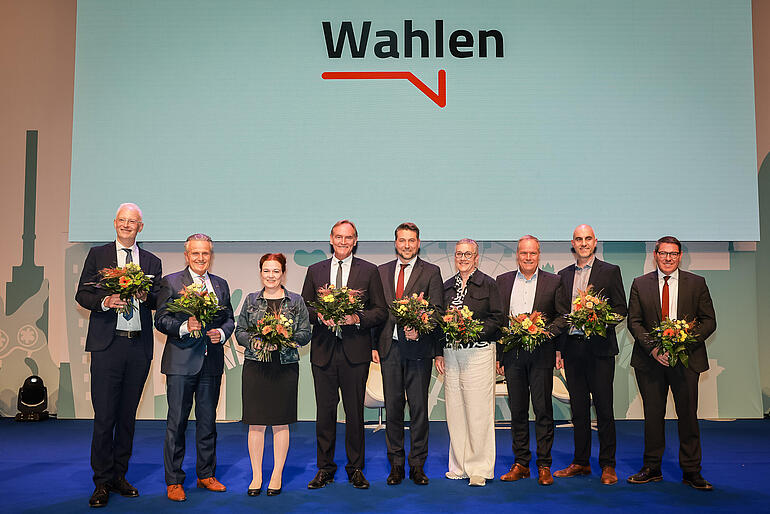 Wolfram Leibe, Frank Nopper, Katja Dörner, Burkhard Jung, Uwe Conradt, Sibylle Keupen, Eckart Würzner, Belit Onay und André Stahl stehen für ein Gruppenfoto auf einer Bühne und halten Blumensträuße.