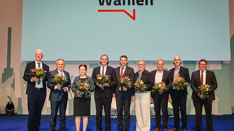 Wolfram Leibe, Frank Nopper, Katja Dörner, Burkhard Jung, Uwe Conradt, Sibylle Keupen, Eckart Würzner, Belit Onay und André Stahl stehen für ein Gruppenfoto auf einer Bühne und halten Blumensträuße.