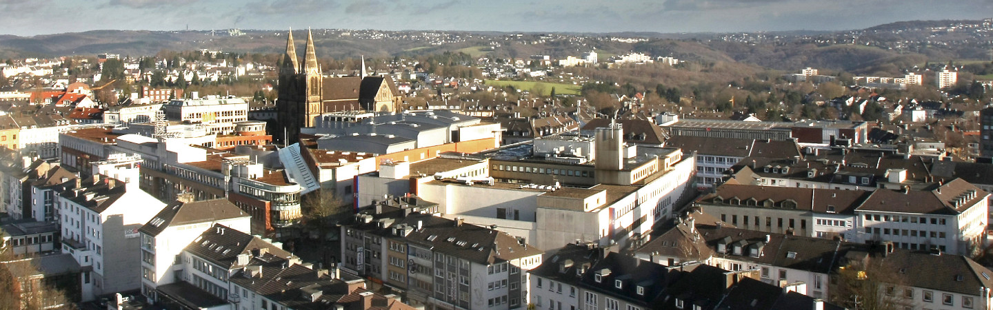 Blick auf die Solinger „City“ mit der katholischen Clemenskirche. Im Hintergrund die östlich angrenzenden Wupperberge mit Teilen des Wuppertaler und Remscheider Stadtgebietes. 